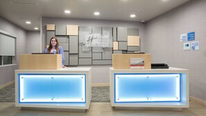 A hotel reception area with two reception desks, a wall-mounted sign, and a bulletin board. - Holiday Inn Express and Suites Lincoln I - 80 by IHG (Lincoln)