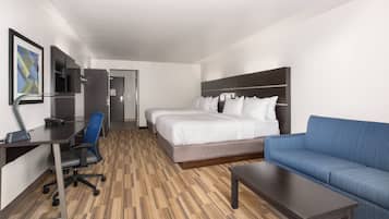 A hotel room with a bed, a sofa, a desk with a chair, and a television.
