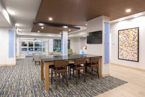 A modern interior with a conference table, chairs, a TV, and a colorful abstract painting.
