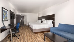 A hotel room with a bed, a blue sofa, a desk with a chair, and a TV. - Holiday Inn Express and Suites Lincoln I - 80 by IHG (Lincoln)