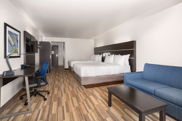 A hotel room with a bed, a blue sofa, a desk with a chair, and a TV. - Holiday Inn Express and Suites Lincoln I - 80 by IHG (Lincoln)