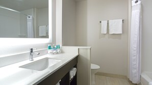 Un baño con lavamanos, espejo y cortina de ducha.