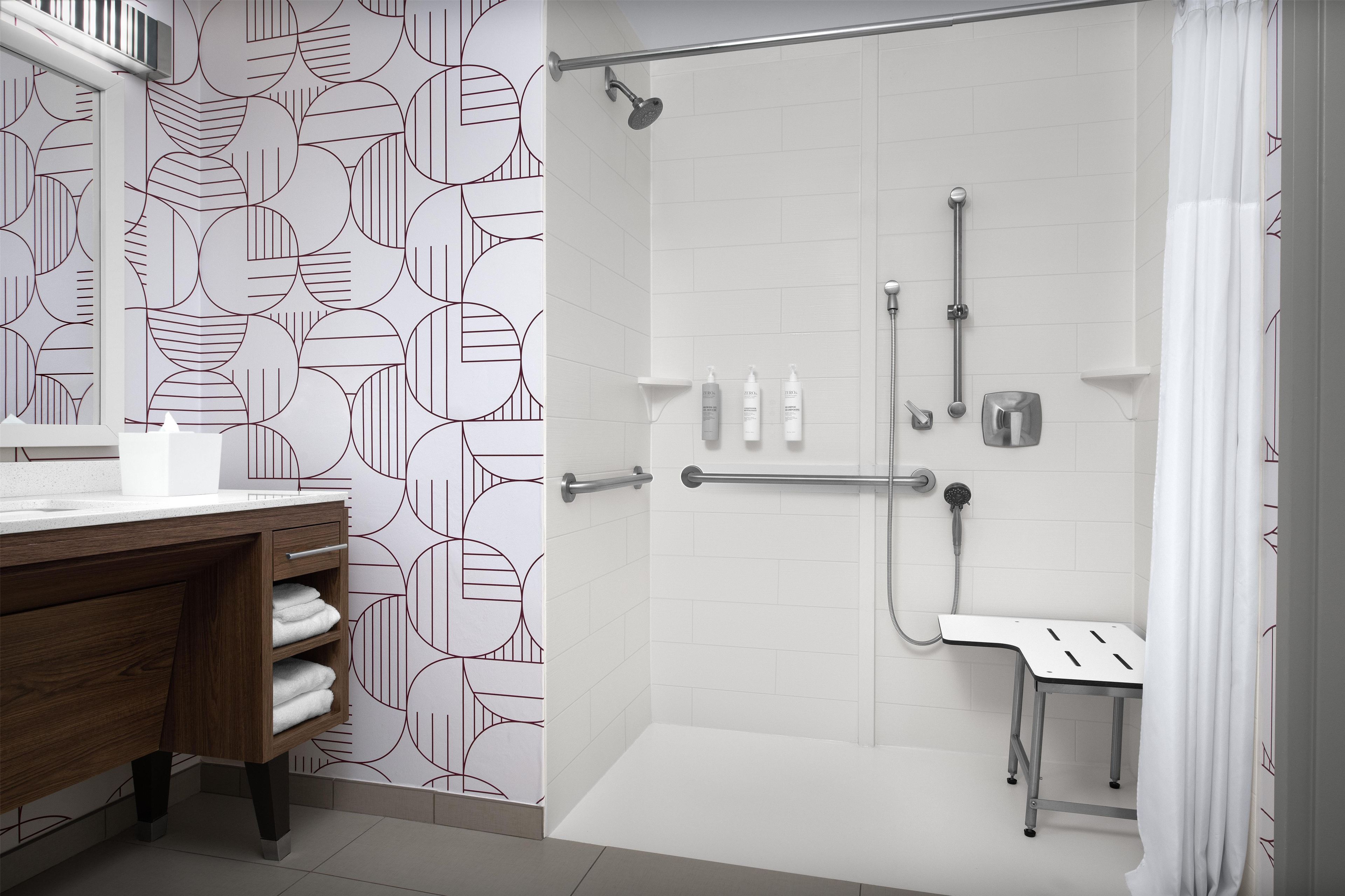 A modern bathroom with a shower, toilet, and a vanity with a mirror and towel rack.