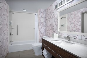 Un baño moderno con ducha, inodoro y tocador con espejo.