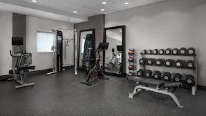 Une salle de sport équipée de matériel d’exercice, d’un miroir et d’un porte-haltères.