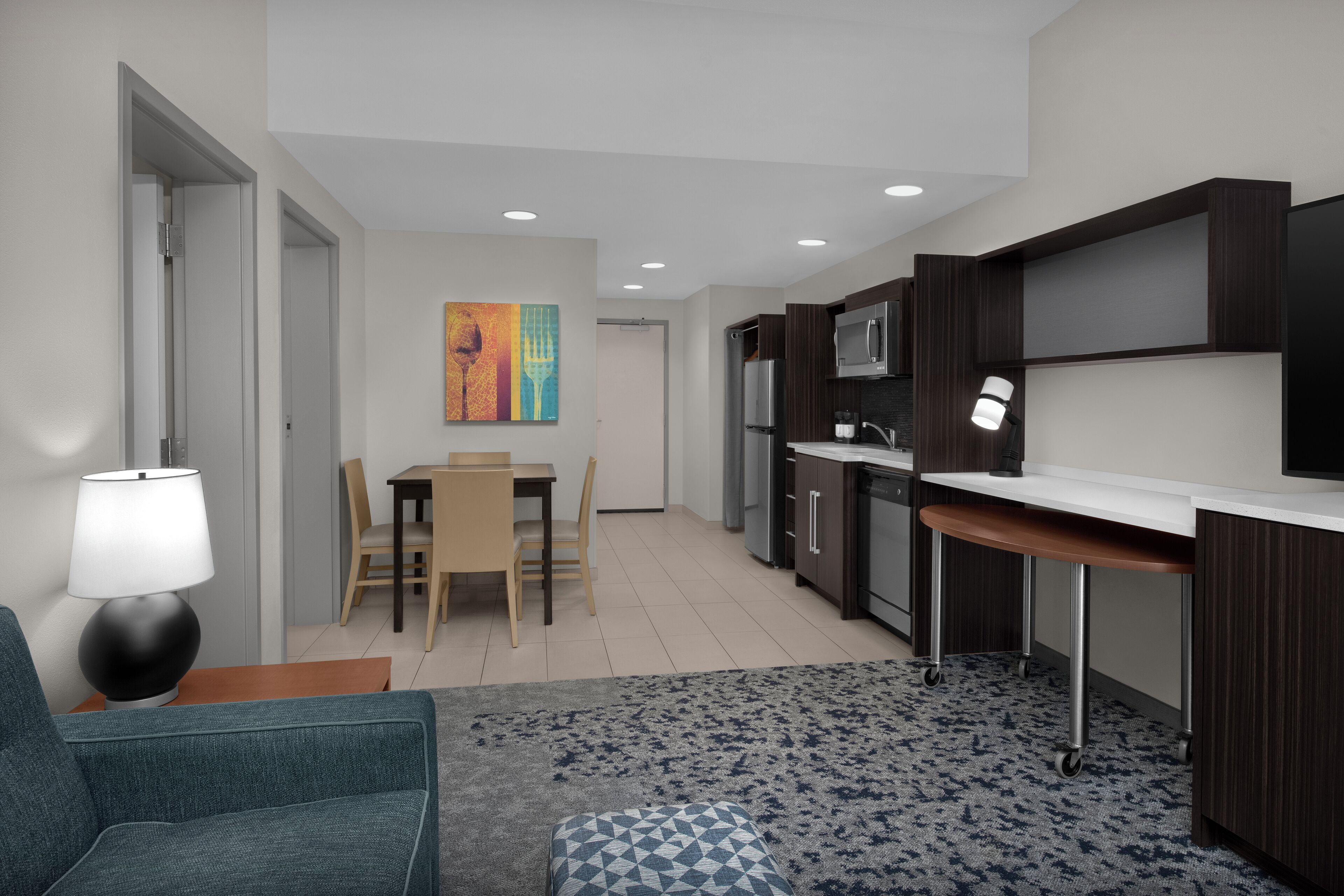 A modern kitchen with dark cabinetry, a microwave, and a dining area with a table and chairs.