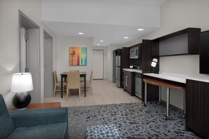 Una cocina moderna con armarios oscuros, un microondas y una zona de comedor con una mesa y sillas.