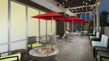 An outdoor patio area with seating, a fire feature, and string lights.