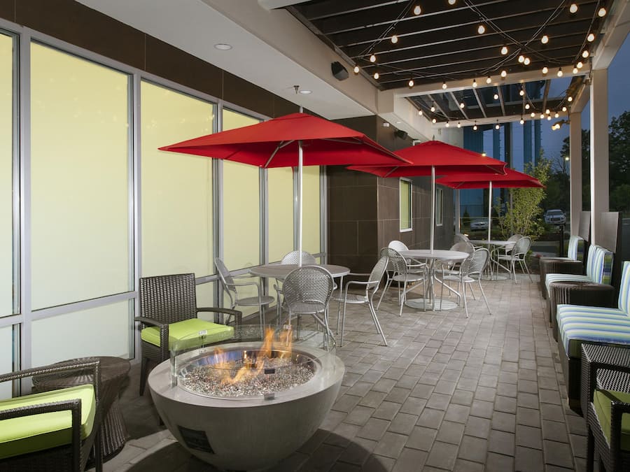 An outdoor patio area with seating, a fire feature, and string lights.