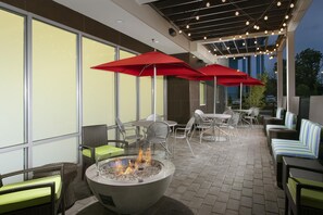 Un patio al aire libre con asientos, una chimenea y luces colgantes.