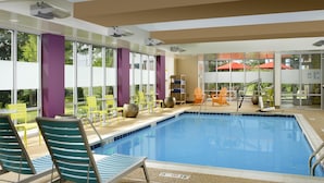 Un espace piscine comprenant des chaises longues, un parasol et une vue sur l’extérieur.