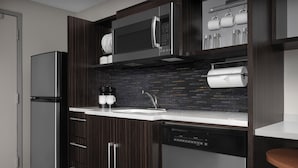 Une cuisine moderne avec des meubles en bois foncé, des appareils électroménagers en acier inoxydable et un dosseret de carreaux noirs.