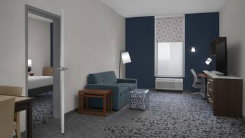 Una habitación de hotel con una cama, un sofá, una mesita, una lámpara, un escritorio y una silla.