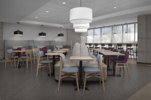 A modern dining area with multiple tables and chairs, pendant lighting, and large windows providing natural light. - Home2 Suites by Hilton Arundel Mills/BWI Airport (Hanover)
