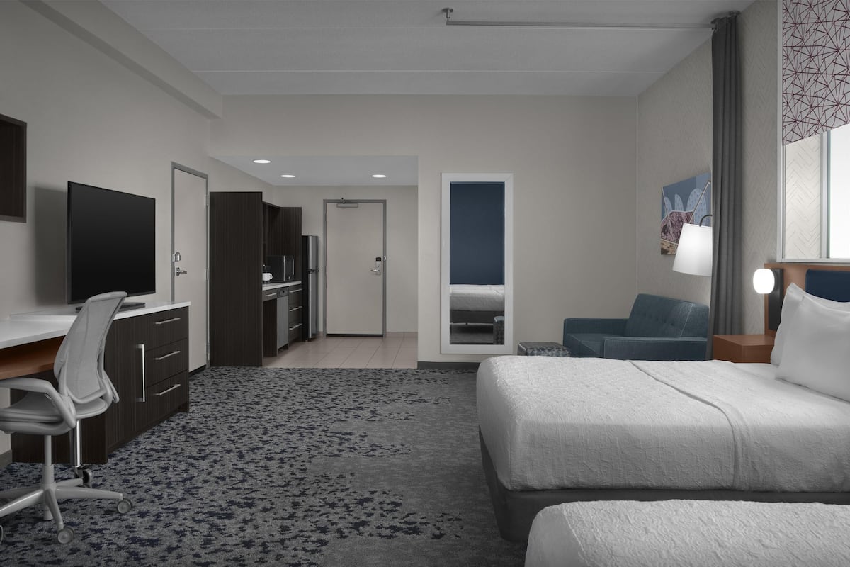 Habitació d'hotel moderna amb llit, escriptori, cadira i televisió.