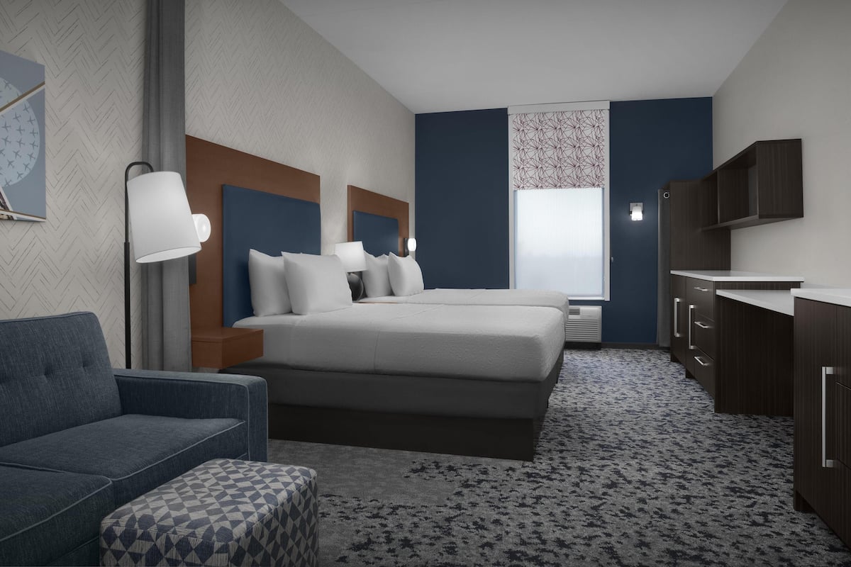 Una habitació d'hotel moderna amb un llit gran, un sofà, un escriptori i un armari.