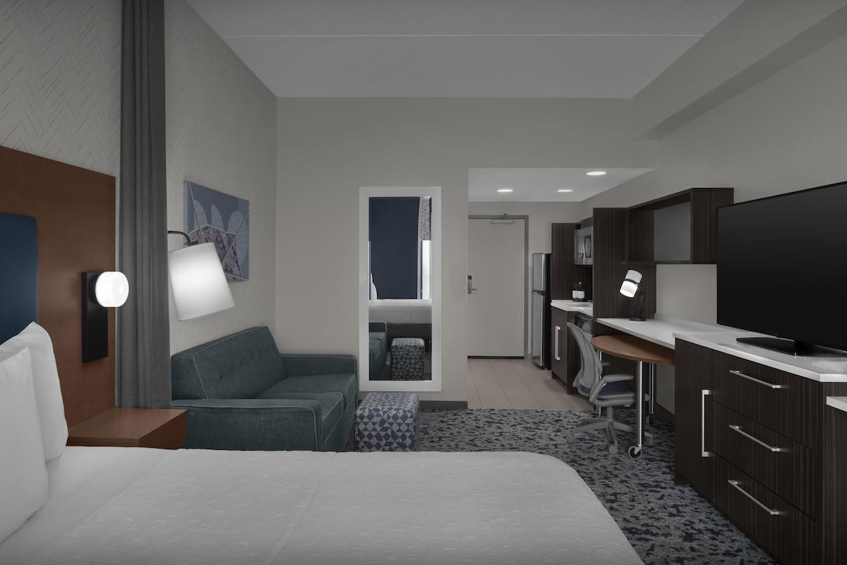 Habitació d'hotel moderna amb un llit gran, escriptori, televisió i zona de seients.