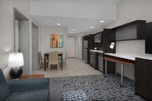 Una cocina moderna con gabinetes oscuros, una encimera blanca y una zona de comedor con mesa y sillas.