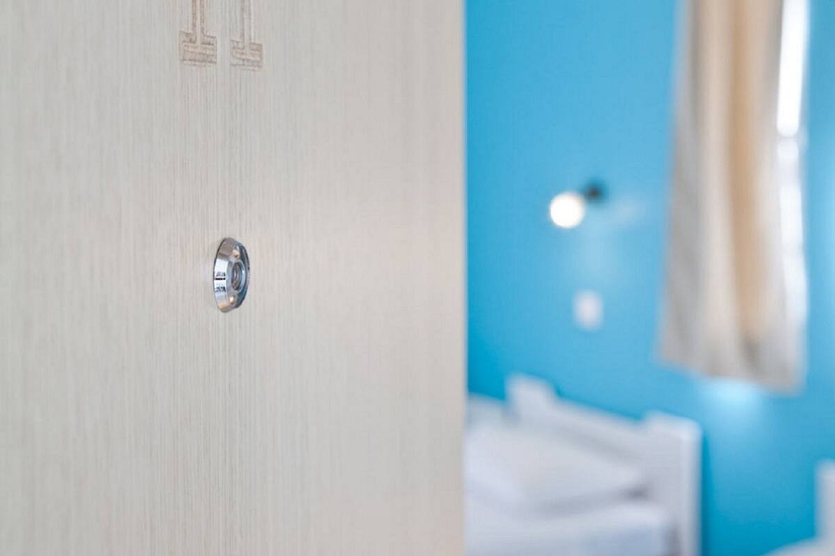 A hotel room with a wooden door, a bed, and a blue wall.