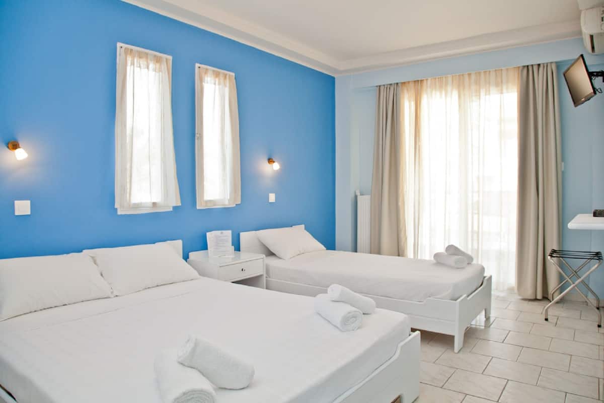 A hotel room with two beds, a TV, and a window with curtains.