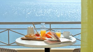 A table with breakfast items and a book, overlooking a body of water. - Pharos Rooms (Istiaia-Aidipsos)
