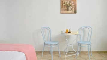 Una habitación con una cama, dos sillas, una mesita con un libro y una taza, y un cuadro en la pared.