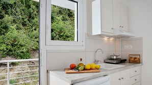A modern kitchen with a window, a sink, and a countertop with fruits and vegetables. - Pharos Rooms (Istiaia-Aidipsos)