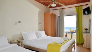 A hotel room with two beds, a wooden ceiling, a TV, and a balcony with a view of the sea. - Pharos Rooms (Istiaia-Aidipsos)