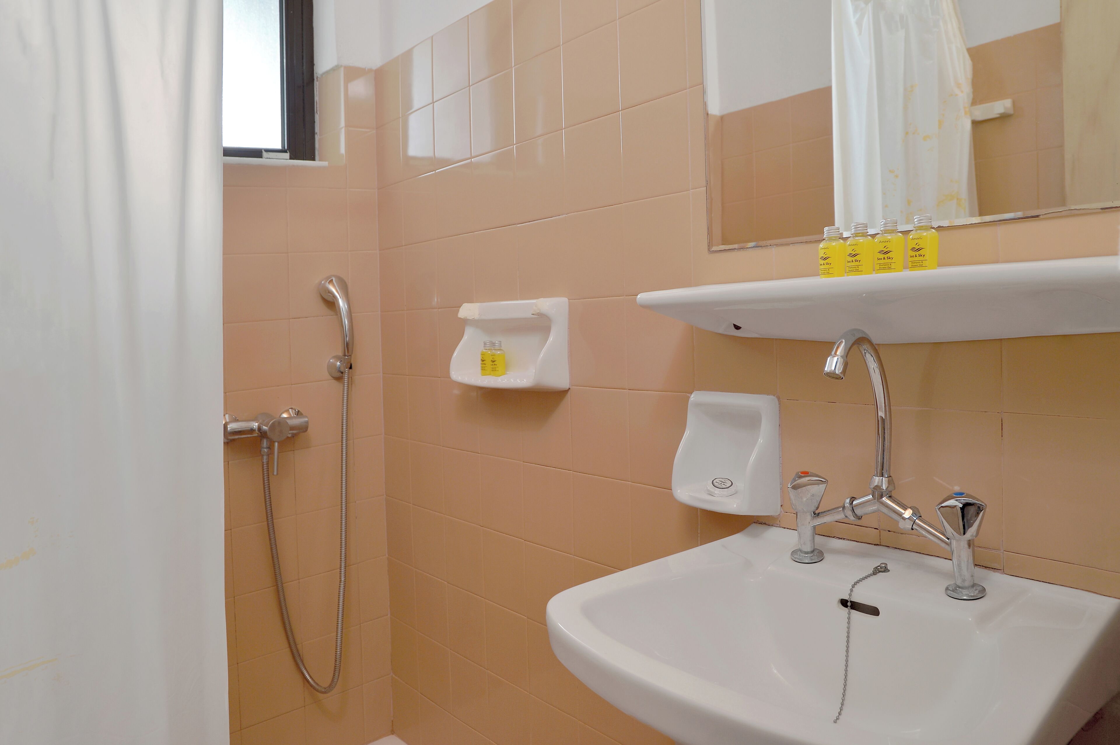 Un baño con ducha, lavamanos y espejo.