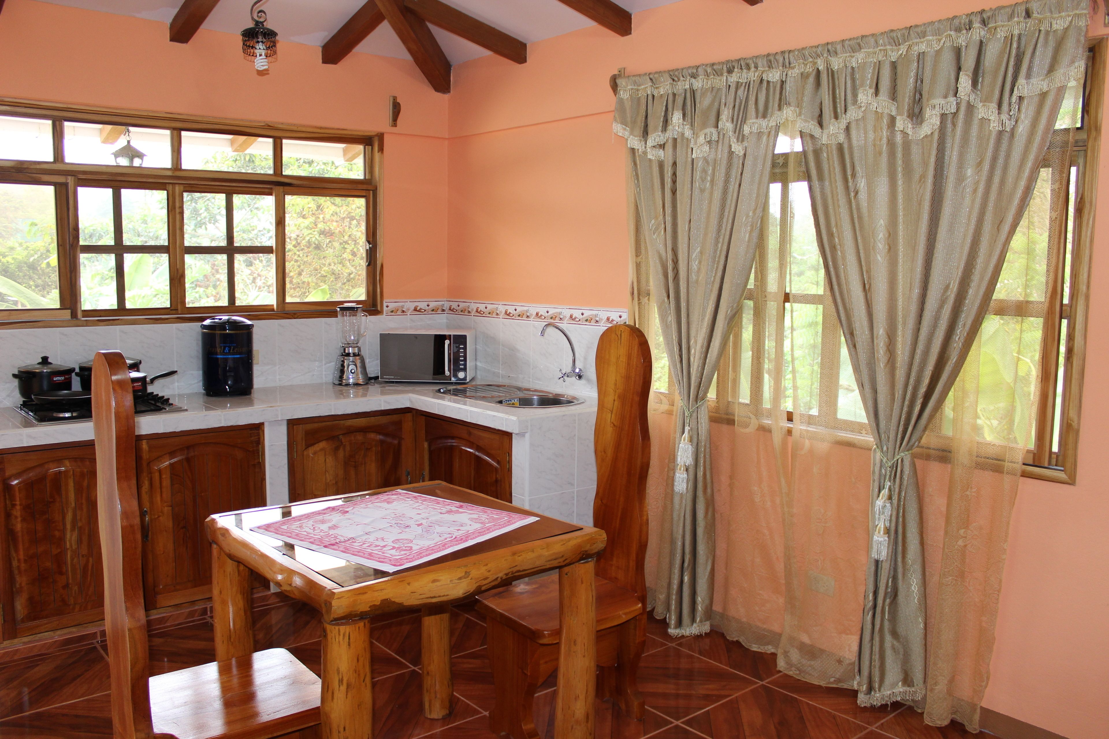 A kitchen with wooden cabinets, a dining table, and a window with curtains.