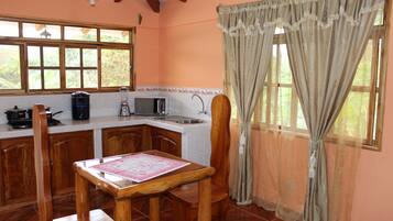 A kitchen with wooden cabinets, a dining table, and a window with curtains.