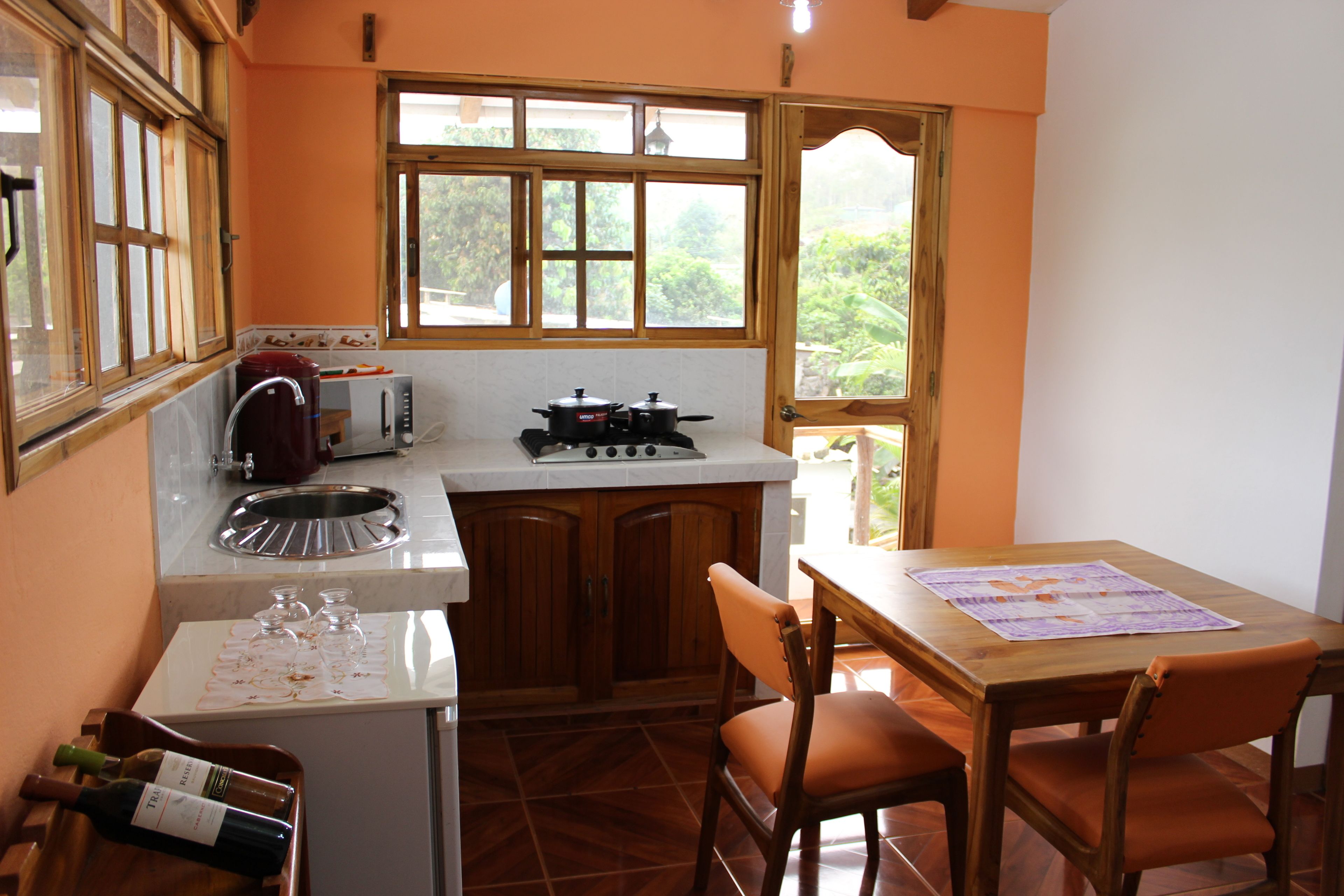 A kitchen with wooden cabinets, a stove, a microwave, and a dining table with chairs.
