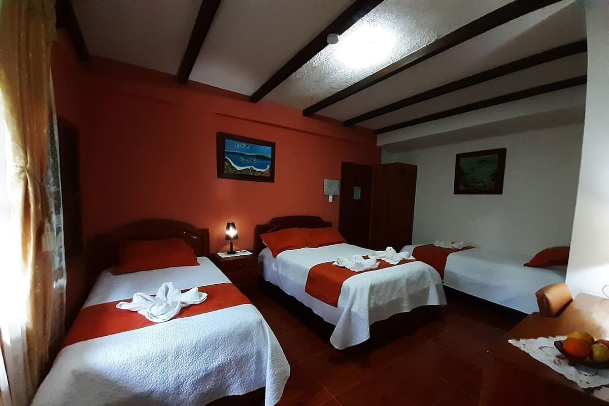 A hotel room with two beds, a wooden ceiling, and a painting on the wall.