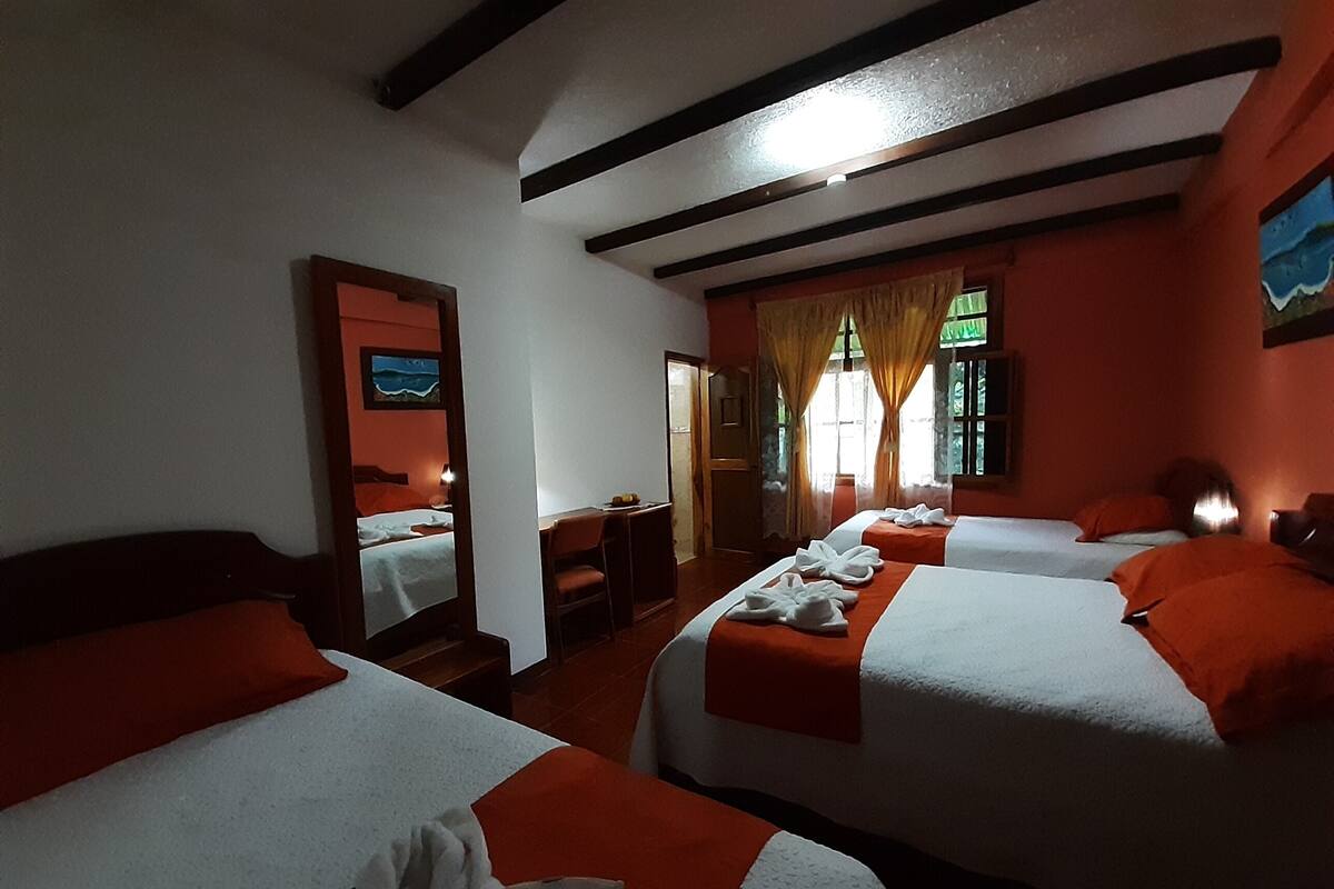 A hotel room with two beds, a desk, and a chair.
