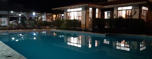 Vista nocturna de una piscina con edificios circundantes.