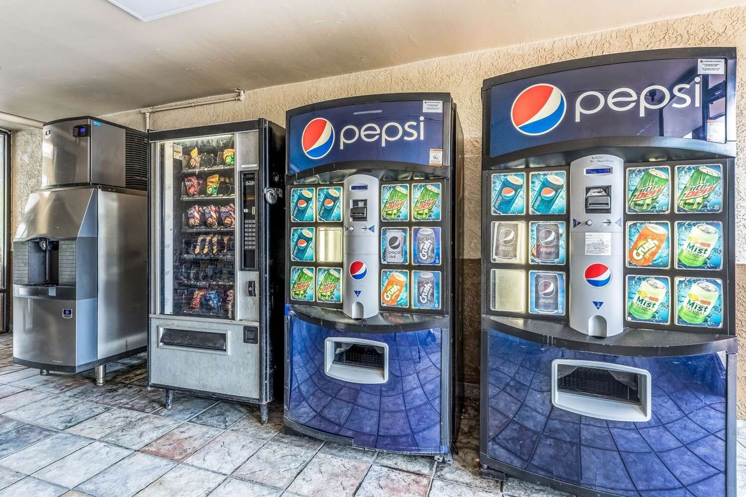 Three beverage vending machines with Pepsi branding, a refrigerated display case, and a beverage dispenser.