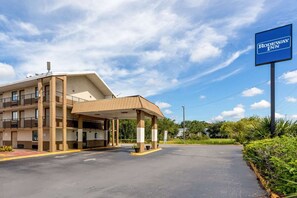 A motel with a covered parking area, a signboard, and a building with multiple floors and balconies. - Tampa Inn Fairgrounds (Tampa)
