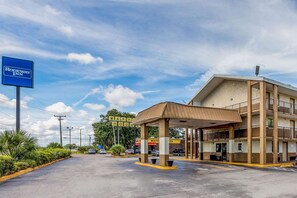 A motel with a covered parking area, a visible sign for a waffle house, and a multi-story building with balconies. - Tampa Inn Fairgrounds (Tampa)