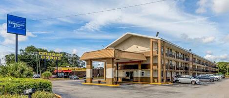 A motel with a covered entrance, a parking lot, and a nearby waffle house.
