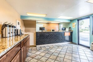 A hotel lobby with a reception desk, a coffee station, and a tiled floor. - Tampa Inn Fairgrounds (Tampa)