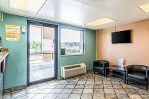 A room with a door, a window, a flat-screen TV, and a seating area with chairs. - Tampa Inn Fairgrounds (Tampa)