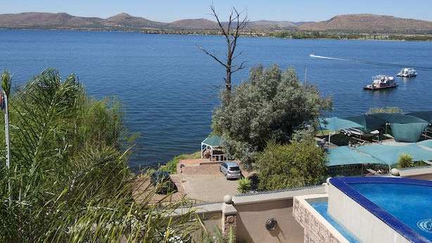 A pool area with a view of a lake and boats. - Kosmos Manor (Hartbeespoort)