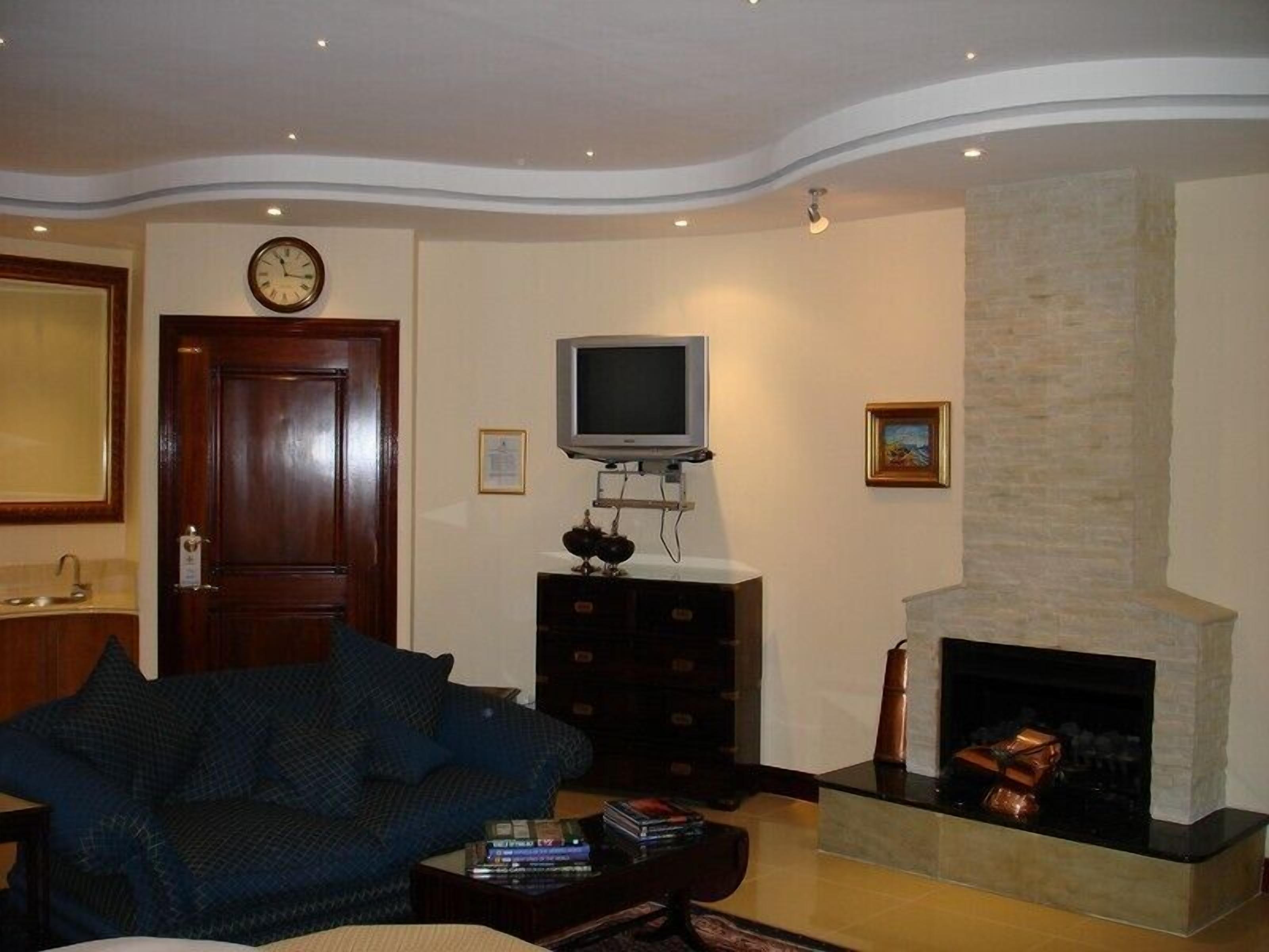 Un salon avec un canapé, un téléviseur, une cheminée et une horloge au mur.