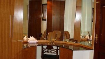 A room with a wooden vanity, a chair, a mirror, and a small rug.