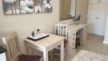 Une chambre à coucher avec un lit en bois, une table de chevet, une chaise, une commode et un miroir.