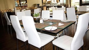 Un espace repas avec une table rectangulaire dressée pour quatre personnes, entourée de chaises blanches.