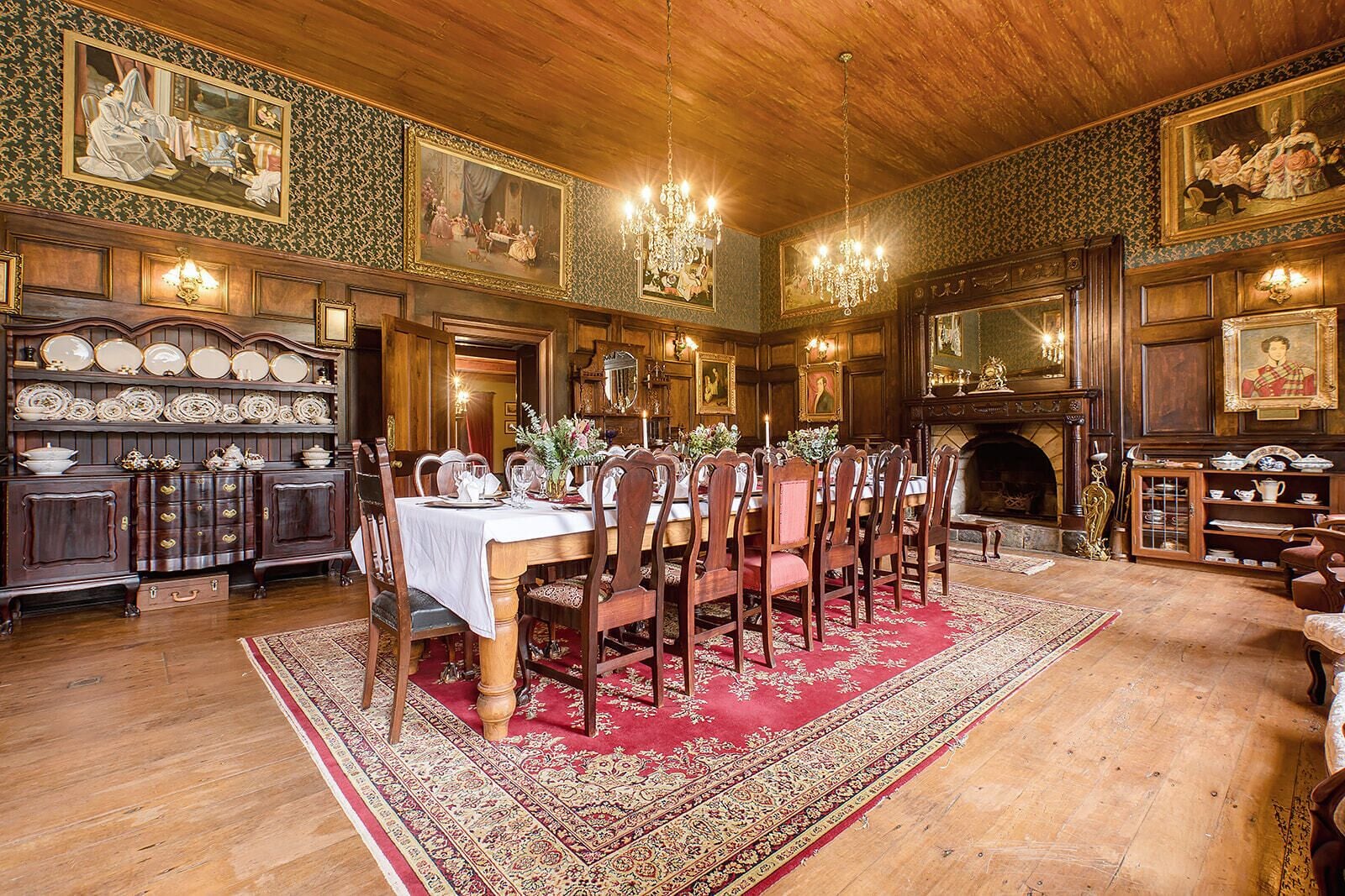 A dining room with a large wooden table set for a meal, surrounded by chairs.
