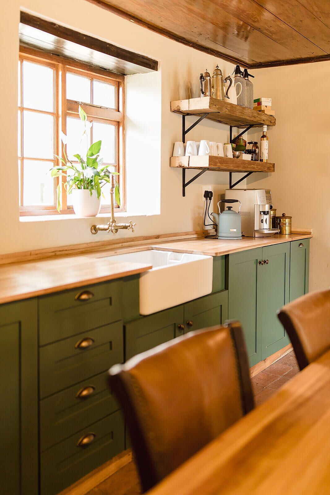 A kitchen with a window, a sink, a coffee maker, and a plant.