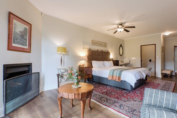 A bedroom with a bed, bedside table, lamp, and a fireplace. - Portland Manor (Knysna)