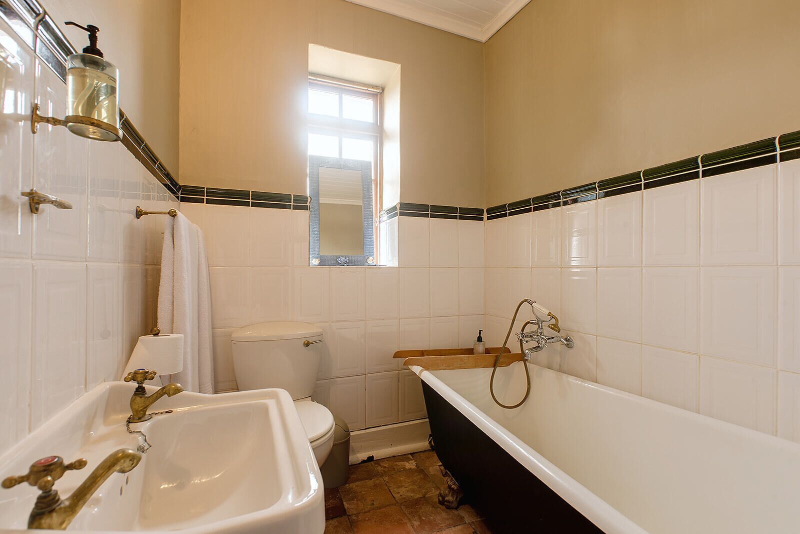 A bathroom with a bathtub, two sinks, a toilet, and a window.